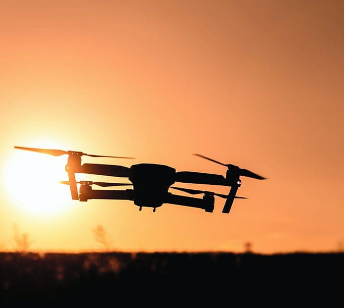 A silhouette of a flying drone in the air.