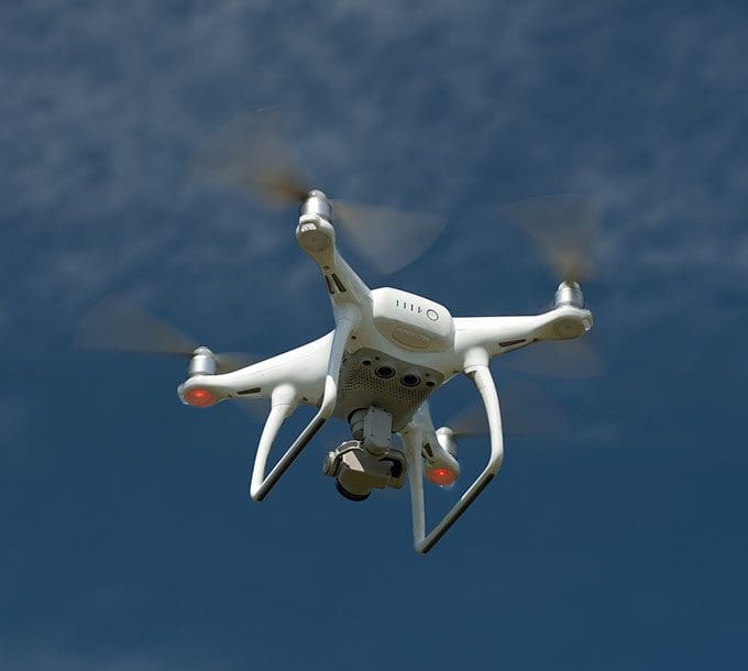 A white drone flying in the air with two propellers.