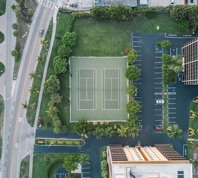 An aerial view of a tennis court and parking lot.