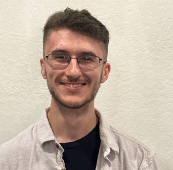 A man with glasses and a shirt smiling for the camera.