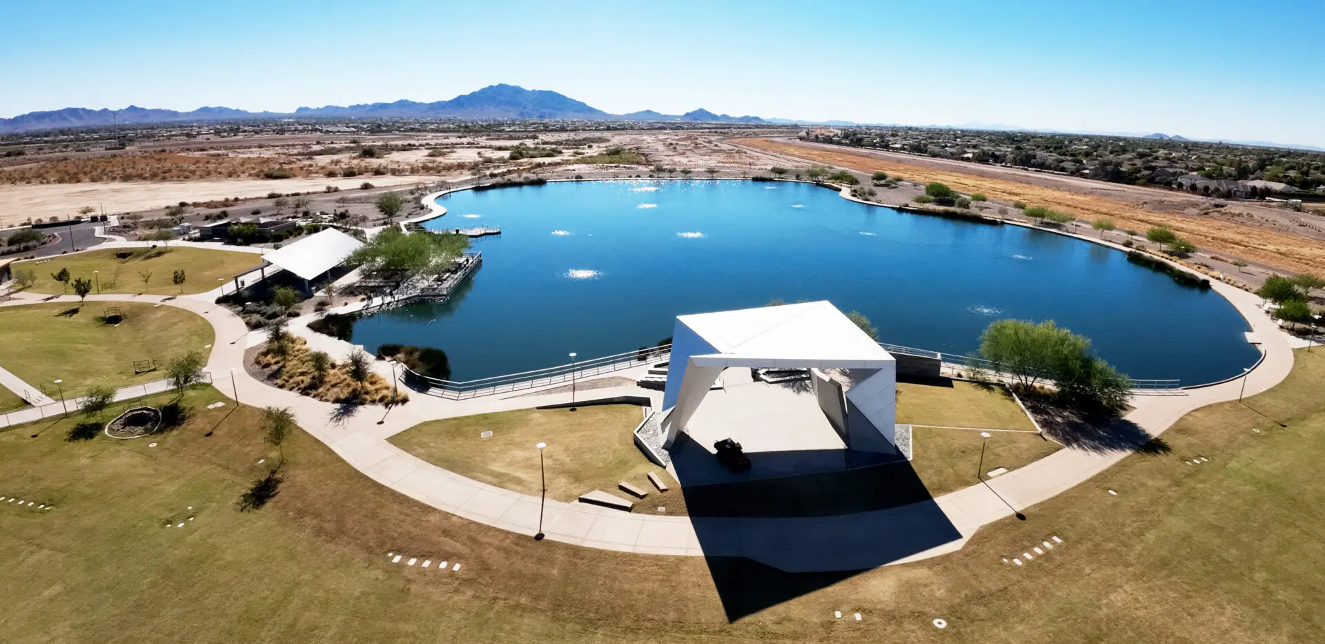 A large pond with a white pavilion in the middle of it.