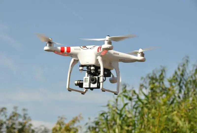 A white and red drone flying in the air.