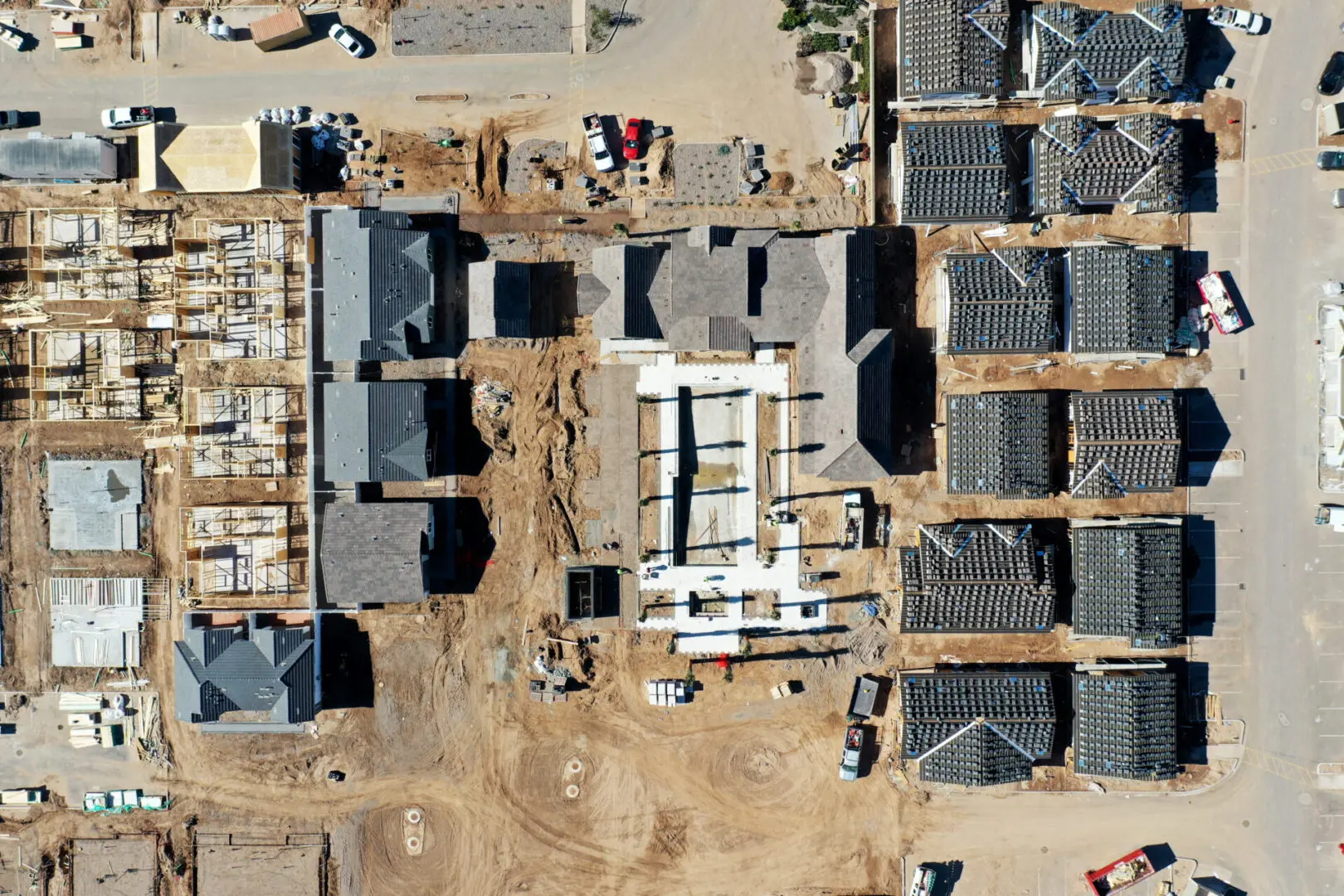 Aerial view of a residential construction site with partially completed buildings and roofing.