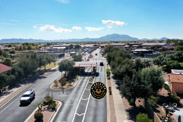 Aerial view of a residential neighborhood with streets lined with houses and vehicles, with mountains in the background on a clear day.