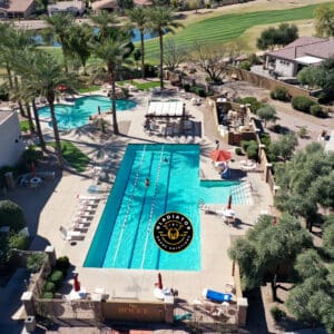 Aerial view of a residential area with a swimming pool, lounging chairs, adjacent golf course, and surrounding homes.