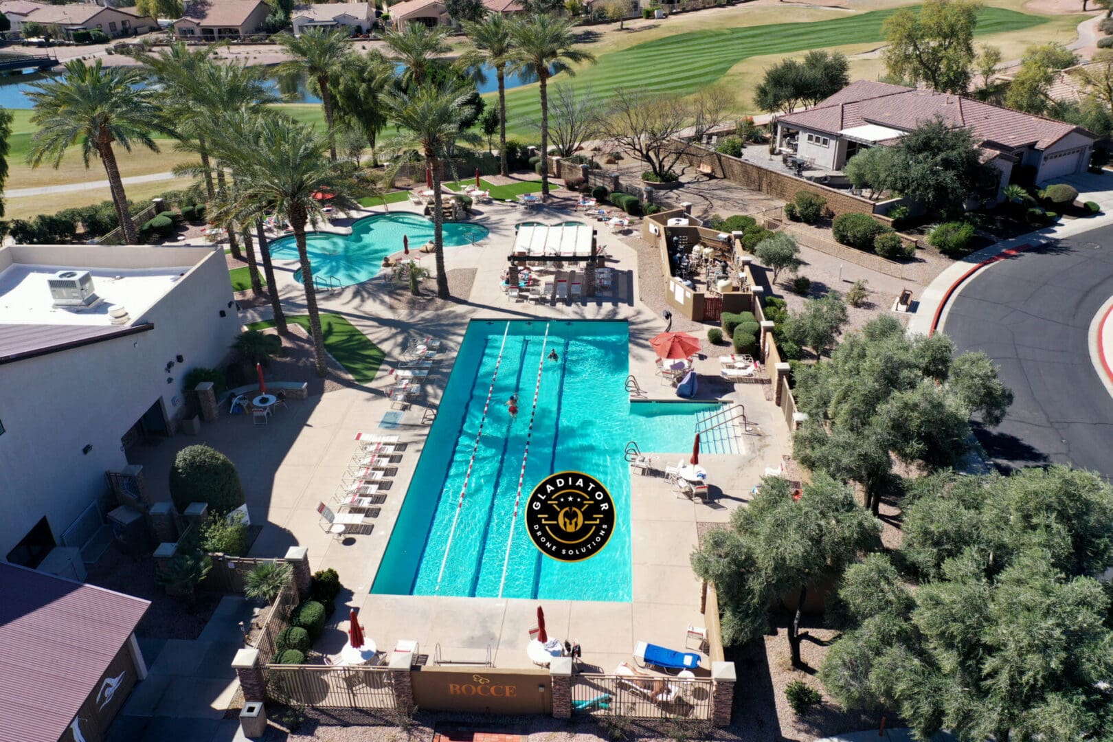 Aerial view of a residential area with a swimming pool, lounging chairs, adjacent golf course, and surrounding homes.