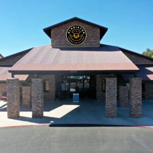 Aerial view of a single-story commercial building with a brown metal roof and stone pillars, featuring a large "cracker barrel" logo above the entrance.