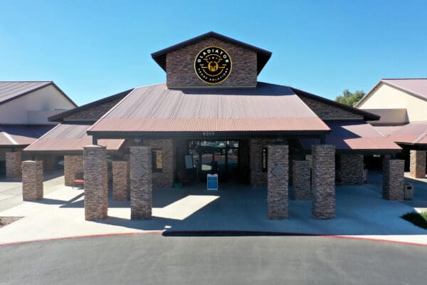 Aerial view of a single-story commercial building with a brown metal roof and stone pillars, featuring a large "cracker barrel" logo above the entrance.