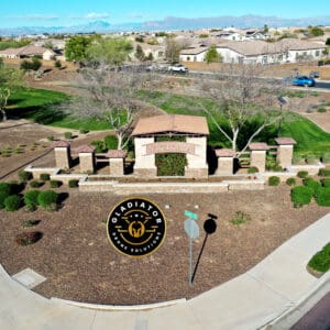 Aerial view of the entrance to a residential area called "victoria," featuring a landscaped roundabout with a decorative sign and seal, surrounded by homes and a clear blue sky.