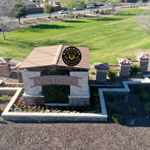 Aerial view of the entrance to victoria, featuring a large sign on a stone wall surrounded by manicured landscaping and green grass.