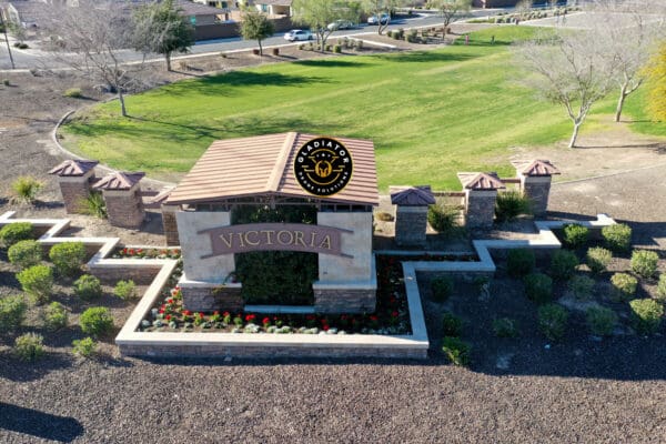 Aerial view of the entrance to victoria, featuring a large sign on a stone wall surrounded by manicured landscaping and green grass.