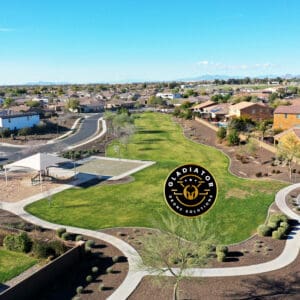 Aerial view of a suburban neighborhood with houses, roads, and a park, under a clear blue sky. a watermark with a logo is visible at the center.