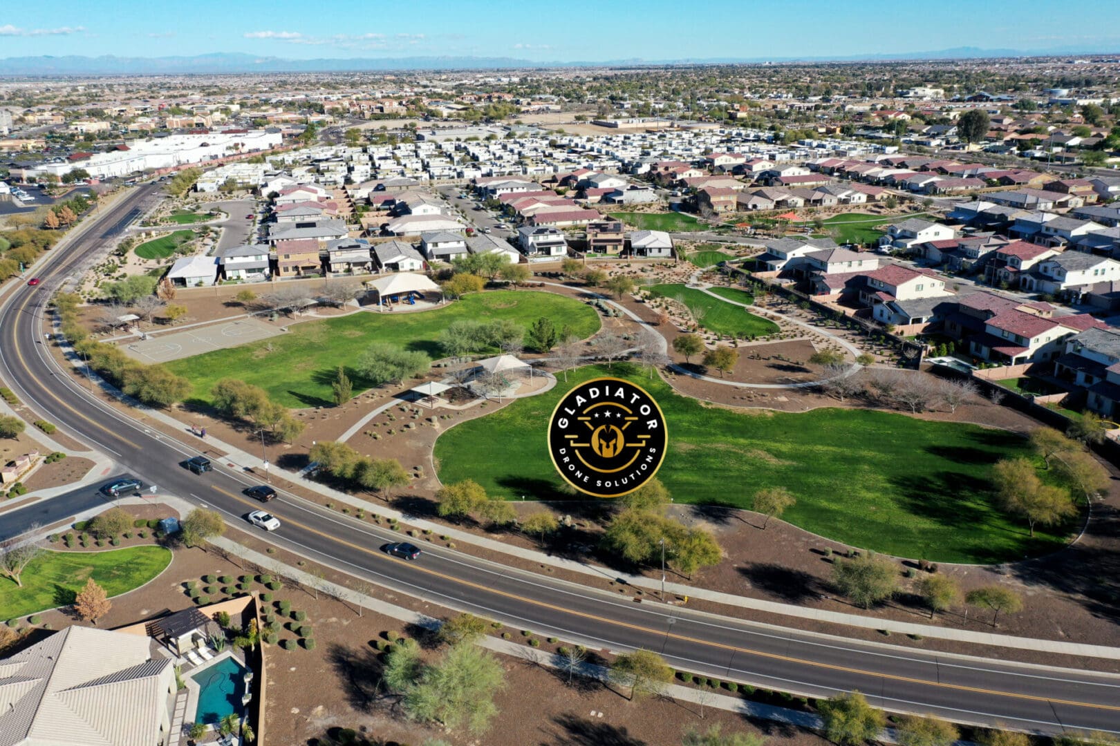 Aerial view of a suburban neighborhood with houses, roads, and a golf course, marked by a circular logo in the center.