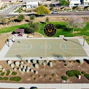 Aerial view of a basketball court in a suburban park with people playing and nearby residential houses.