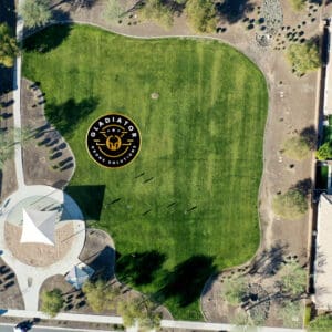 Aerial view of a residential area with a green park showcasing a large emblem and star design on the grass.