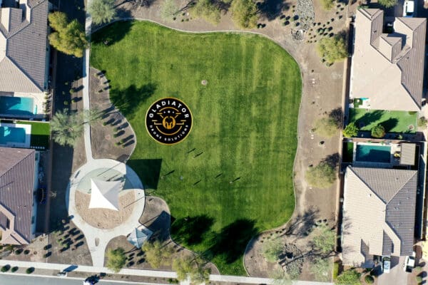 Aerial view of a residential area with a green park showcasing a large emblem and star design on the grass.